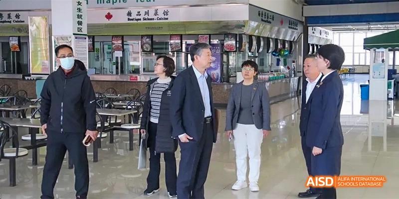 A man and a woman walking and talking inside a building at Maple Leaf International High School - Dalian