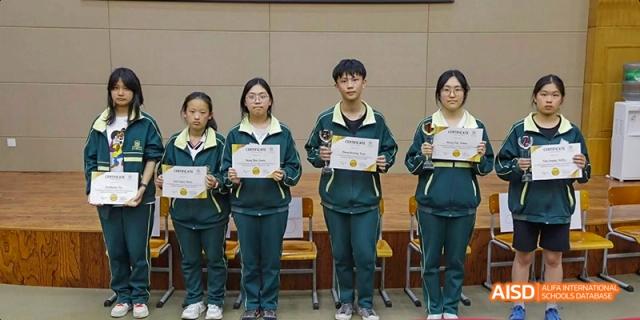 Students from Maple Leaf International High School - Dalian standing on a stage, holding certificates.