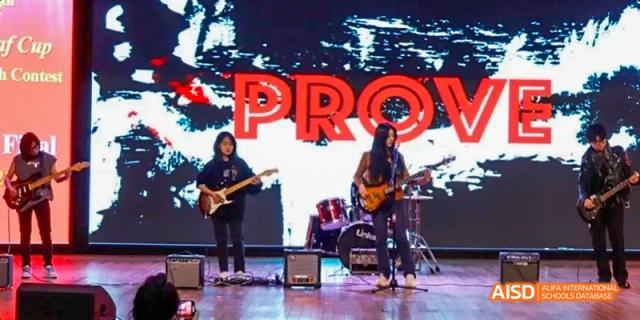 A student from Maple Leaf International High School - Dalian playing an electric guitar with a band on stage.