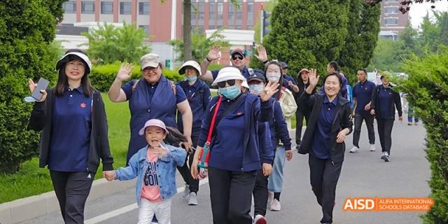 Students and adults from Maple Leaf International High School - Dalian walking in a group, one person is wearing a mask.