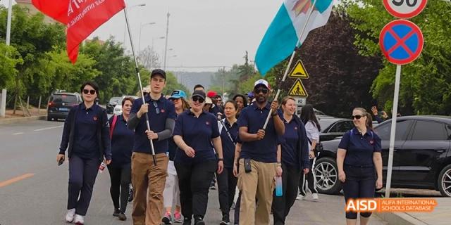 A group of students from Maple Leaf International High School - Dalian marching in a parade, some carrying flags.