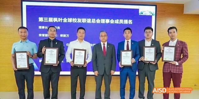 Three men from Maple Leaf International High School - Dalian holding awards while standing and smiling for the camera.