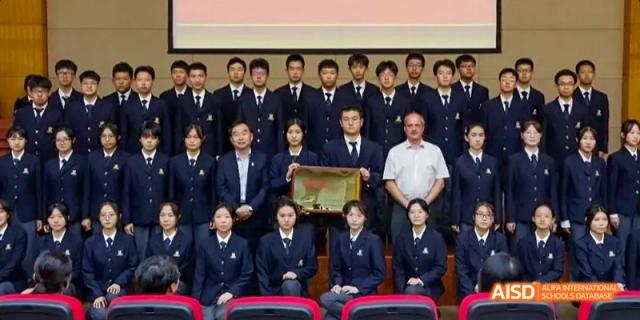 A group photo of students and teachers from Maple Leaf International High School - Dalian posing with a trophy.