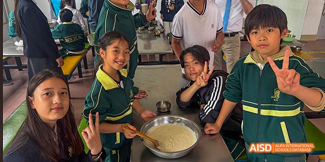 A group of students from Maple Leaf International High School - Dalian are smiling for a photo while eating.