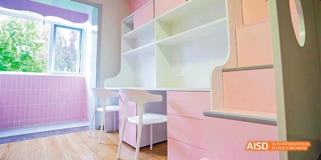 A modern common area at Beijing Aidi School with white and pink furniture.