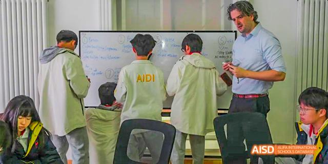 A teacher and a student from Beijing Aidi School working together at a whiteboard with "AIDI" written on it.
