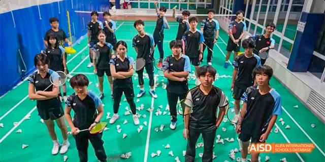 Beijing Aidi School badminton team posing for a group photo on a court littered with shuttlecocks