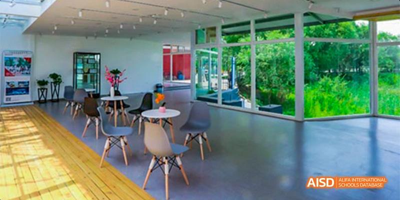 The interior of a modern-looking cafe or common area at Beijing Aidi School with chairs and tables.