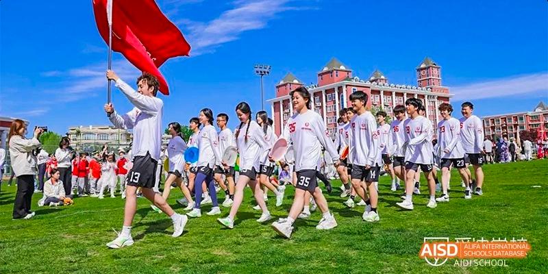 Beijing Aidi School students running and participating in an outdoor activity on a grassy field.
