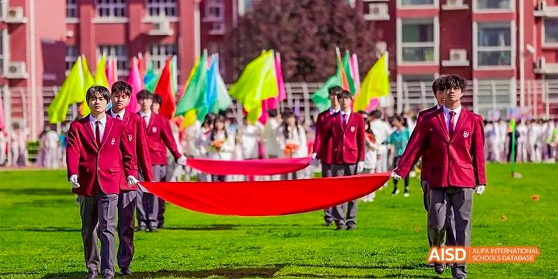 Students holding a large red banner during a parade or event at Beijing Aidi School.