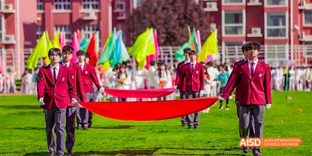 Students holding a large red banner during a parade or event at Beijing Aidi School.