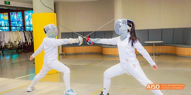 Two students from Beijing Aidi School practicing fencing indoors.