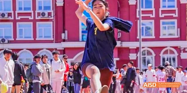 A female student from Beijing Aidi School in a blue shirt running during a track and field event.