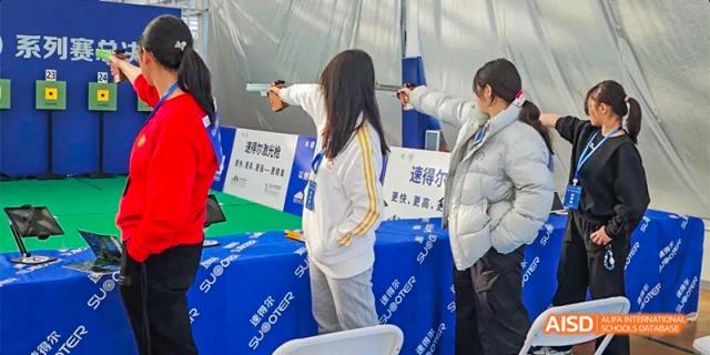 A student at Beijing Aidi School aiming a practice gun in a shooting activity.