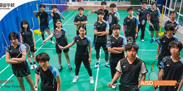 The Beijing Aidi School badminton team posing for a group photo in black uniforms.