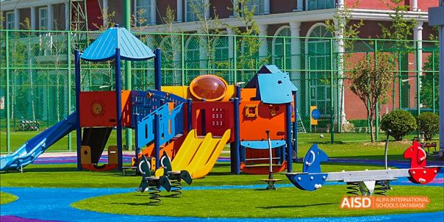 A colorful playground with a slide and a small climbing wall at Beijing Aidi School.