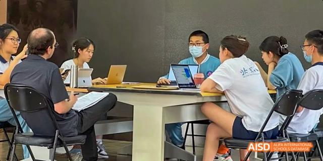 A Beijing No.8 High School student, wearing a face mask, uses a laptop during a class or academic activity.