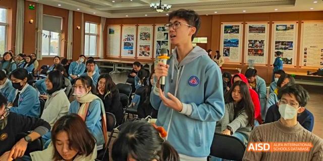 A Beijing No.8 High School student is speaking into a microphone while giving a presentation to an audience.