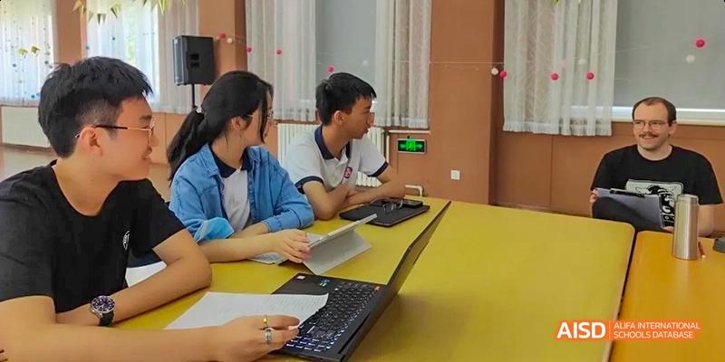 Two Beijing No.8 High School students collaborating and working on a laptop and keyboard at a yellow desk.