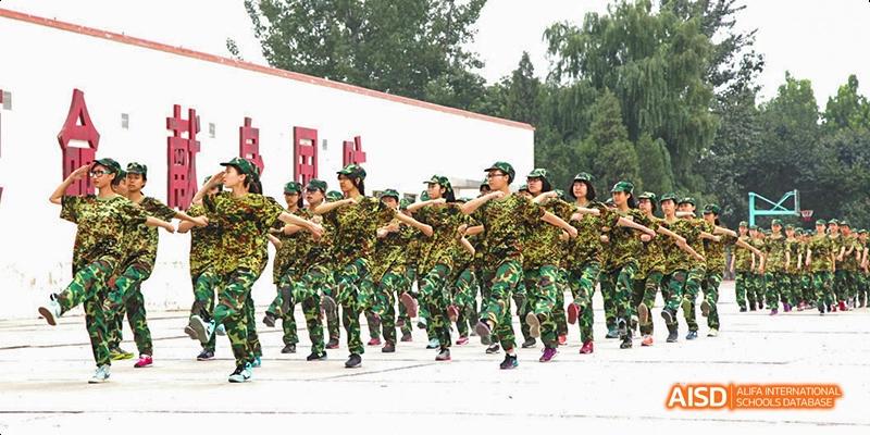A group of Beijing No.8 High School students in camouflage uniforms marching or performing a drill outside.