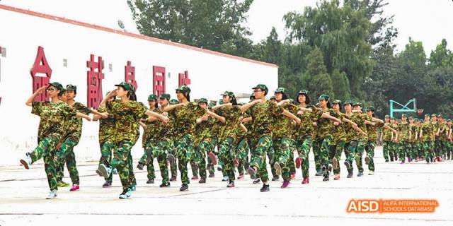 A group of Beijing No.8 High School students in camouflage uniforms marching or performing a drill outside.