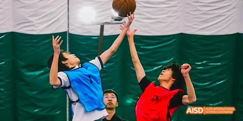 Two Beijing No.8 High School students jumping for a rebound or block during a game of basketball on an indoor court.