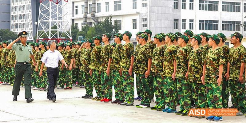 A line of Beijing No.8 High School students in camouflage uniforms standing in formation outdoors.