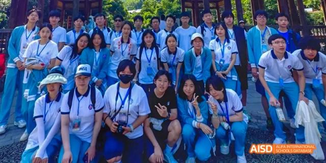 A large group of Beijing No.8 High School students posing for a group photo outdoors, some kneeling in front.