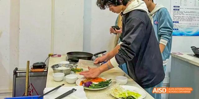 A Beijing No.8 High School student preparing and cutting vegetables on a cutting board next to a stove during a cooking session.
