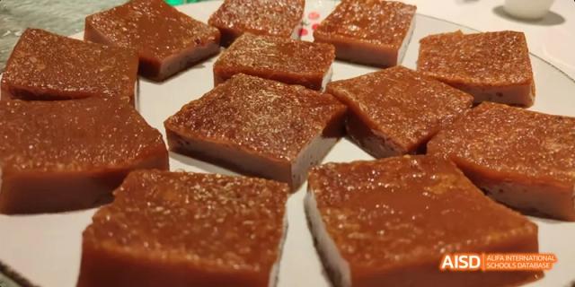 A close-up view of squares of a reddish, dense, and savory meat preparation from a culinary class at Beijing No.8 High School.