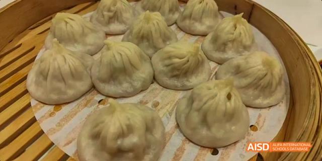 A close-up of a platter of freshly steamed soup dumplings (Xiaolongbao), made by students at Beijing No.8 High School.