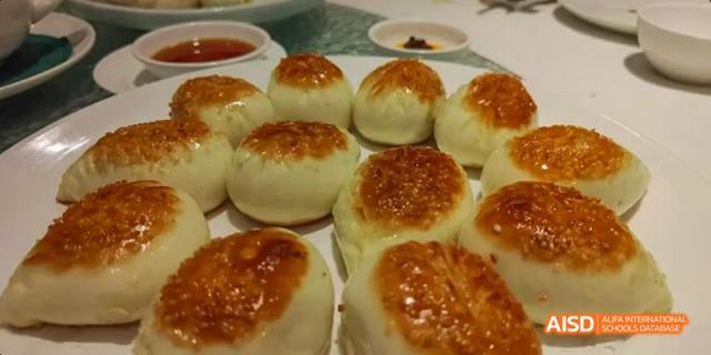 A platter of freshly baked, round pastries with a shiny, browned tops from a Beijing No.8 High School culinary arts class.