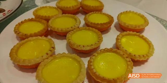 A close-up of multiple individual Portuguese egg tarts with yellow custard filling, baked by students at Beijing No.8 High School.