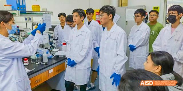 Chengdu Shishi High School Beihu Campus AP Curriculum students wearing lab coats and safety glasses in a science lab.