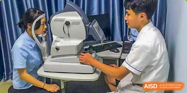 Chengdu Shishi High School Beihu Campus AP Curriculum student practicing using an eye exam machine for optometry training.