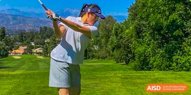 Chengdu Shishi High School Beihu Campus AP Curriculum student practices their golf swing on a green field.