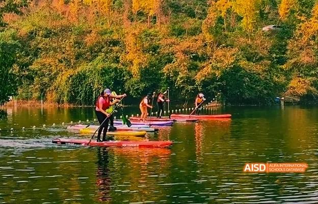 People paddleboarding on a lake in the autumn at Chongqing Depu Foreign Language School