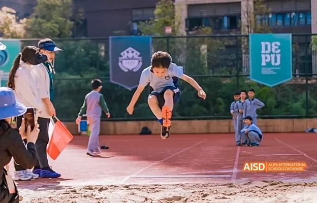 A young boy doing a long jump at Chongqing Depu Foreign Language School