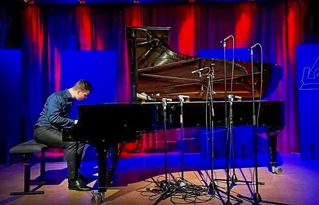 A grand piano on a stage with a red curtain at Chongqing Depu Foreign Language School