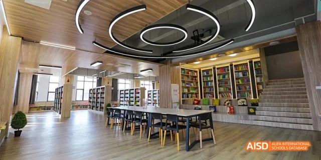 The interior of a modern library or collaborative study area with unique circular ceiling lights and tables at DongGuan Laguna Verona Foreign Language School.