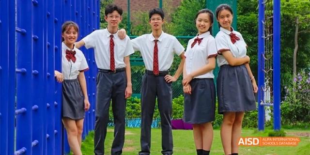 A group of high school students in white shirts, ties, and dark skirts/pants standing together and smiling outdoors at DongGuan Laguna Verona Foreign Language School.