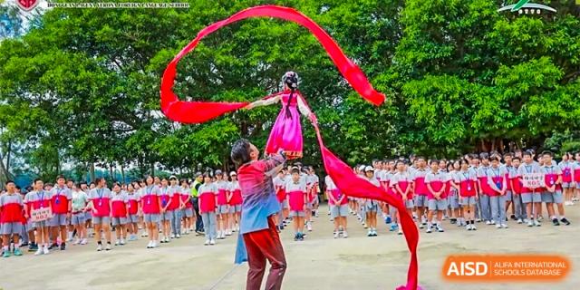 Students performing a ribbon dance during an outdoor event or exercise in front of a large group at DongGuan Laguna Verona Foreign Language School.