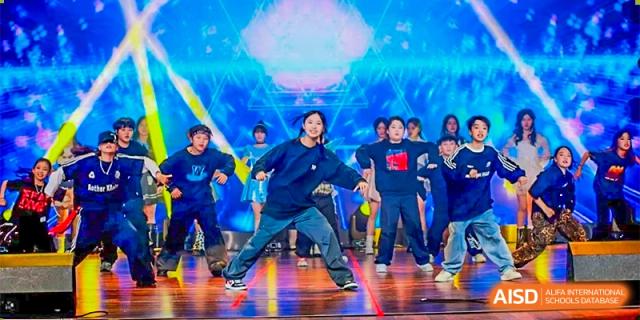 A group of students performing a dance routine on a brightly lit stage during an event at DongGuan Laguna Verona Foreign Language School.