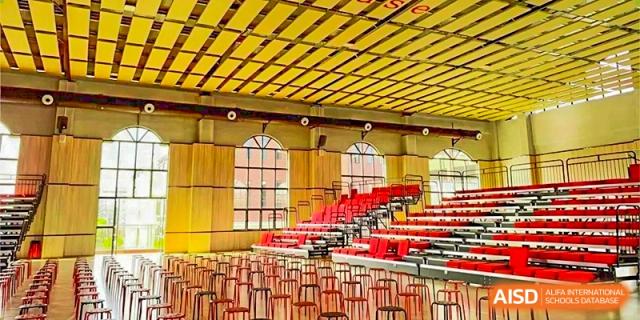 Interior view of the empty red and yellow seating in an indoor gymnasium or auditorium at DongGuan Laguna Verona Foreign Language School.