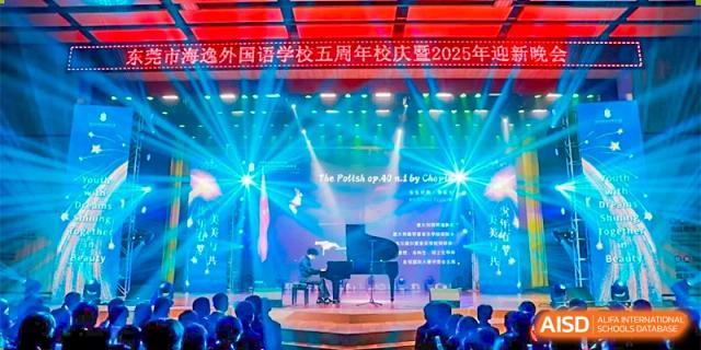 A student playing a piano on a large stage with bright blue and white lighting during a school celebration at DongGuan Laguna Verona Foreign Language School.