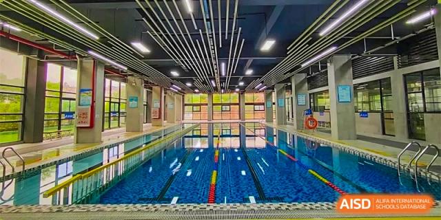 The modern, well-maintained indoor swimming pool facility with blue tiled lanes and a bright ceiling at DongGuan Laguna Verona Foreign Language School.