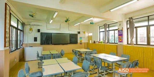 An interior shot of a well-lit classroom with individual desks, chairs, and large screens at the front, ready for students at GDUFS International School Guangzhou.