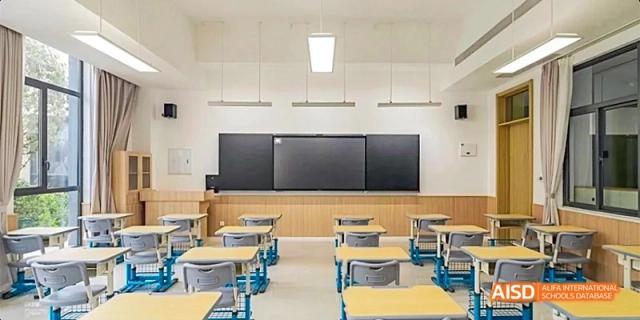 An interior shot of a modern classroom featuring a wall of digital screens and adjustable desks, demonstrating the learning environment at GDUFS International School Guangzhou.