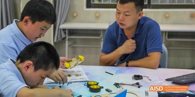 Students working on a hands-on design or engineering project with small parts and materials spread on a table at GDUFS International School Guangzhou.