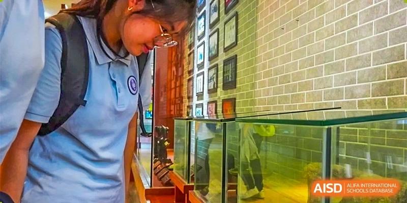 Students looking closely at an exhibit behind a glass case during a museum or gallery visit at GDUFS International School Guangzhou.